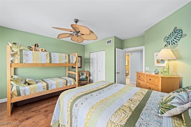 bedroom featuring visible vents, a ceiling fan, wood finished floors, a closet, and baseboards