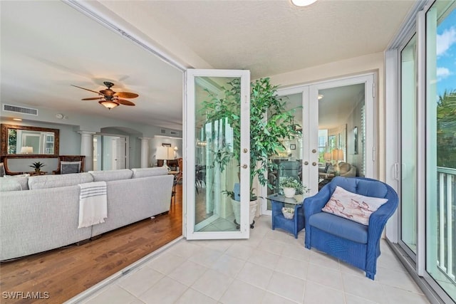 interior space featuring visible vents, ceiling fan, decorative columns, french doors, and arched walkways