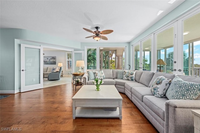 living area featuring a wealth of natural light, baseboards, wood finished floors, and ceiling fan