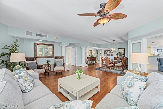 living area with visible vents, arched walkways, wood finished floors, and decorative columns