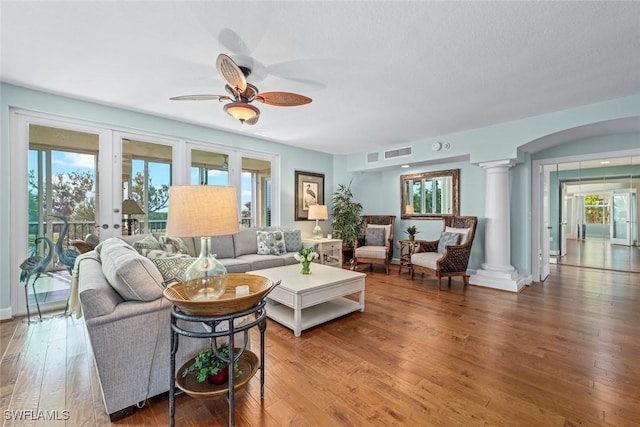 living room with decorative columns, wood finished floors, visible vents, and plenty of natural light