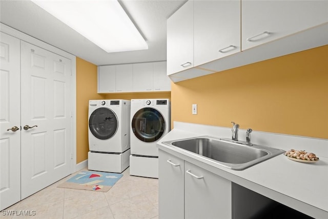 washroom featuring a sink, cabinet space, light tile patterned flooring, and washer and dryer