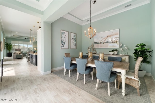 dining space with light wood-type flooring, a raised ceiling, visible vents, and an inviting chandelier