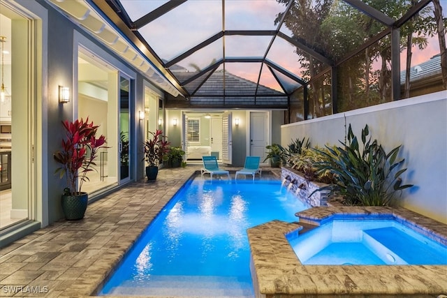 pool at dusk with a patio and a pool with connected hot tub