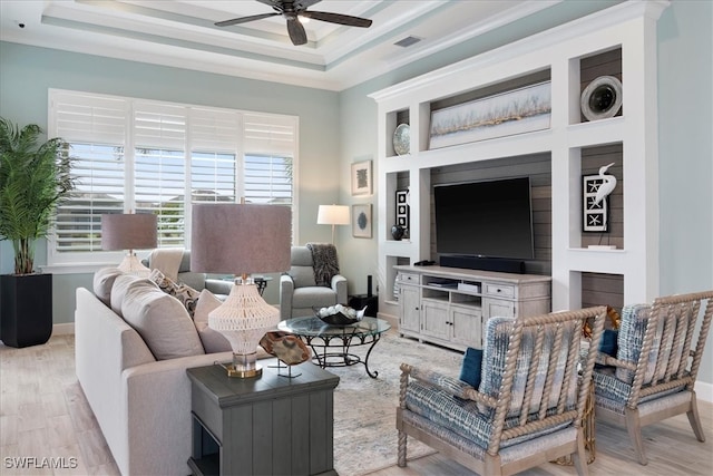 living room featuring visible vents, a raised ceiling, baseboards, ceiling fan, and light wood-style flooring