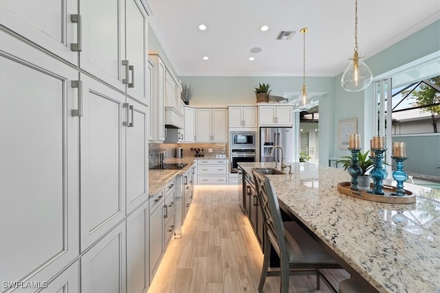 kitchen featuring light stone counters, pendant lighting, stainless steel appliances, visible vents, and a sink