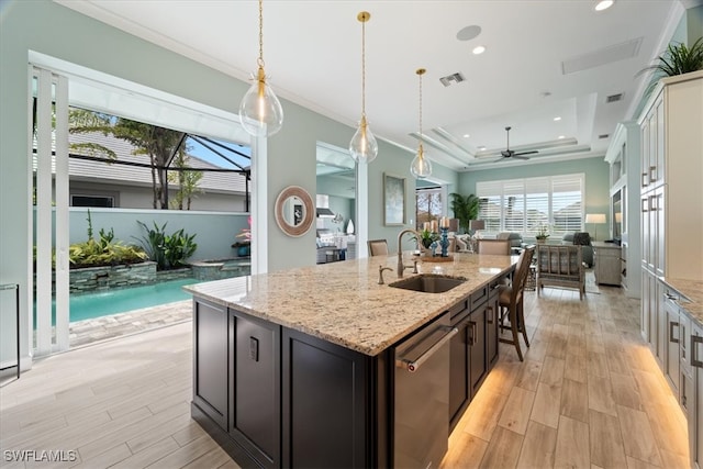 kitchen with a sink, visible vents, dishwasher, a tray ceiling, and crown molding