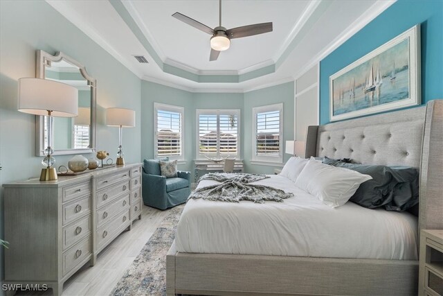 bedroom featuring visible vents, a raised ceiling, a ceiling fan, ornamental molding, and light wood-style floors