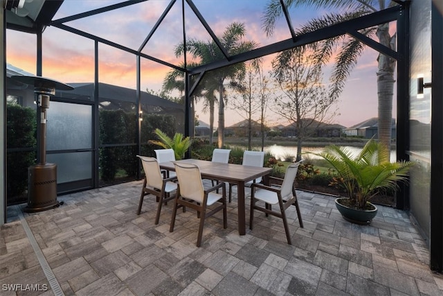 patio terrace at dusk featuring outdoor dining space and a lanai