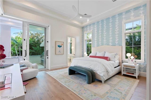 bedroom featuring wallpapered walls, baseboards, multiple windows, and access to exterior