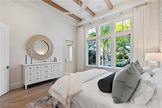 bedroom with wood finished floors, a towering ceiling, visible vents, baseboards, and beam ceiling