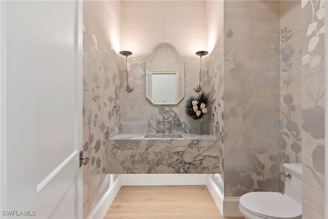 full bathroom with toilet, a tile shower, and wood finished floors