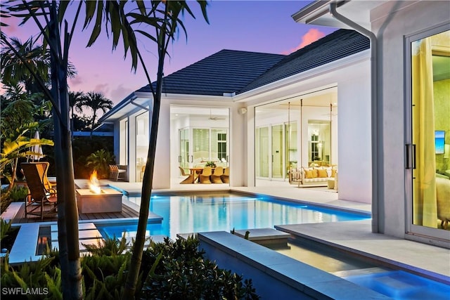 outdoor pool featuring an outdoor living space with a fire pit and a patio