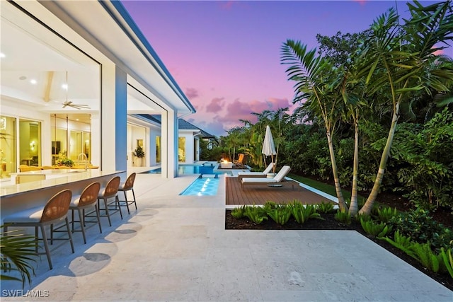 patio terrace at dusk with an outdoor pool and outdoor dry bar