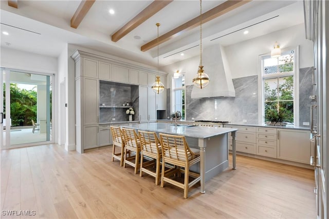 kitchen featuring light wood finished floors, tasteful backsplash, beamed ceiling, gray cabinetry, and premium range hood