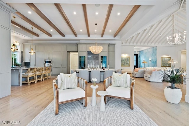 living area featuring a chandelier, a high ceiling, beamed ceiling, and light wood-style floors