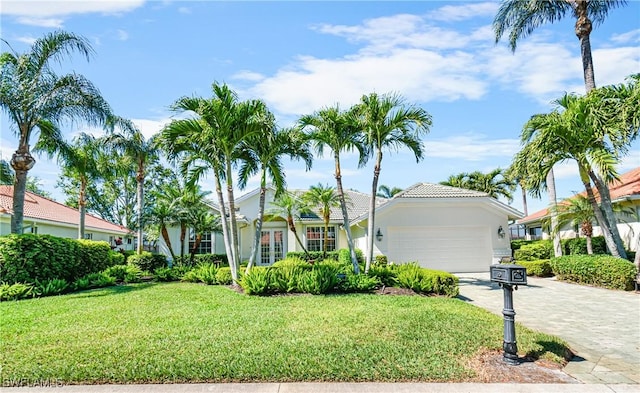 view of front of home with a front yard, decorative driveway, and a garage