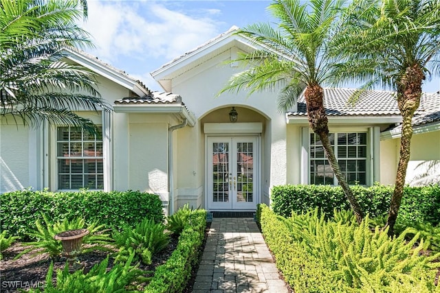 doorway to property with a tiled roof, french doors, and stucco siding