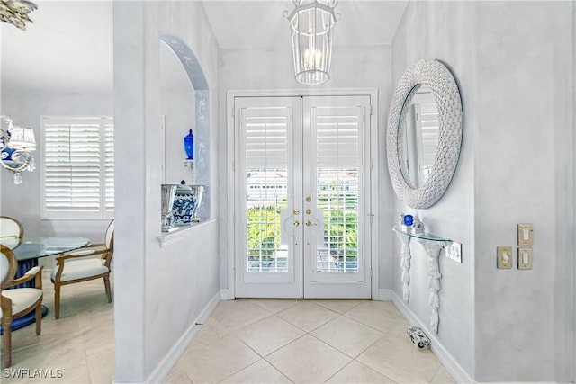 foyer featuring tile patterned flooring, a chandelier, french doors, and baseboards