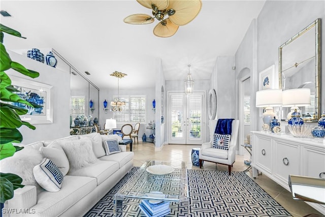 living area featuring light tile patterned floors, french doors, arched walkways, and ceiling fan with notable chandelier