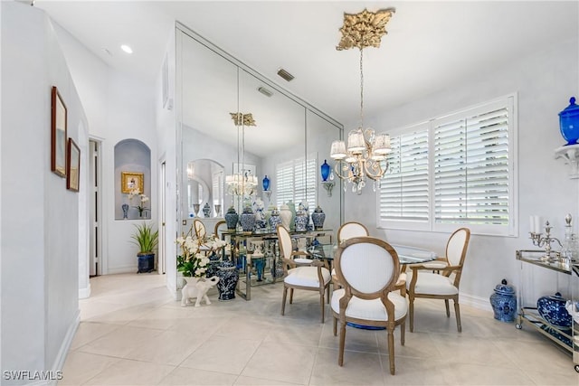 dining area with light tile patterned floors, visible vents, arched walkways, vaulted ceiling, and a chandelier