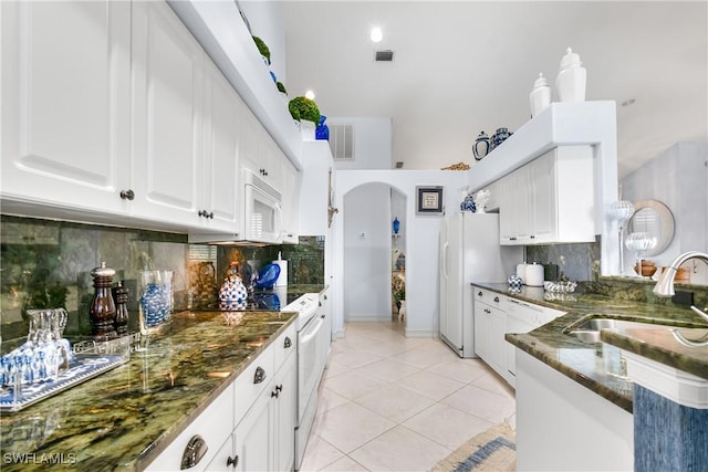 kitchen featuring light tile patterned floors, visible vents, arched walkways, and white appliances