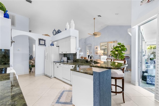 kitchen featuring arched walkways, light tile patterned floors, white appliances, and a peninsula