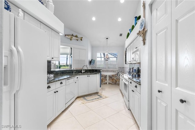 kitchen featuring white appliances, light tile patterned floors, a sink, white cabinets, and dark countertops