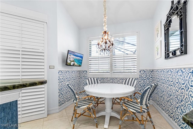 dining space with tile patterned flooring, a wainscoted wall, breakfast area, and a notable chandelier