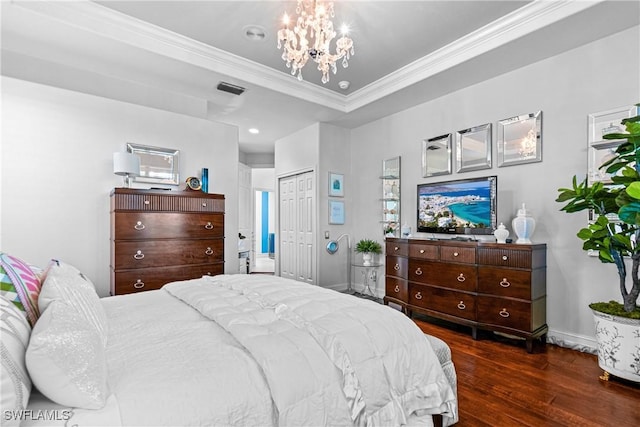 bedroom featuring visible vents, a notable chandelier, ornamental molding, a tray ceiling, and wood finished floors