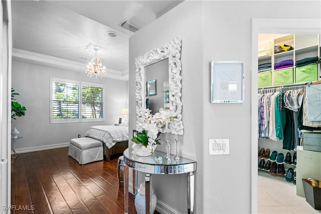 interior space with visible vents, crown molding, baseboards, an inviting chandelier, and wood-type flooring