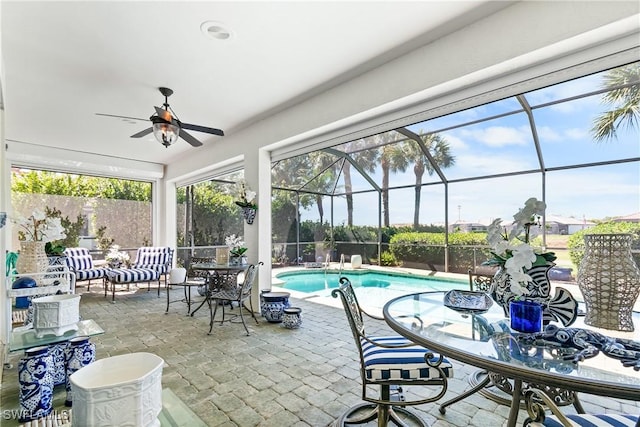 view of patio / terrace featuring a lanai, an outdoor pool, outdoor dining area, and a ceiling fan