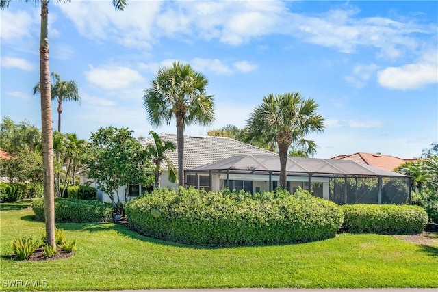 view of front of house featuring glass enclosure, a tile roof, and a yard