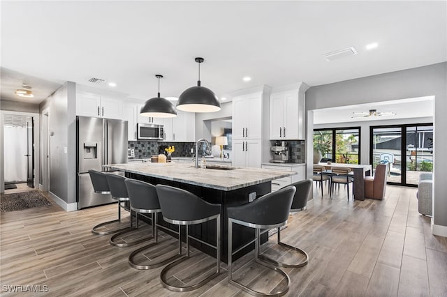 kitchen with visible vents, appliances with stainless steel finishes, a breakfast bar, white cabinetry, and a sink