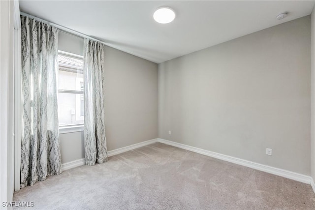 spare room featuring carpet floors and baseboards