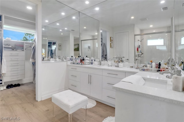 bathroom with wood finished floors, a shower stall, vanity, and a walk in closet