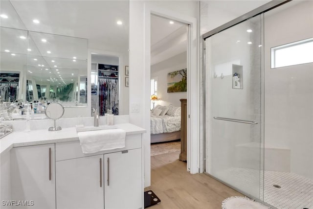 bathroom with recessed lighting, a spacious closet, a stall shower, vanity, and wood finished floors