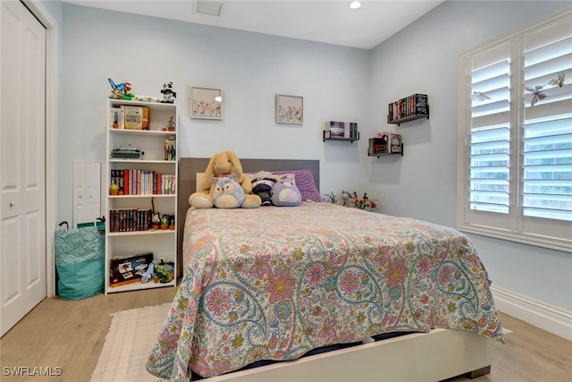 bedroom with a closet, wood finished floors, and baseboards