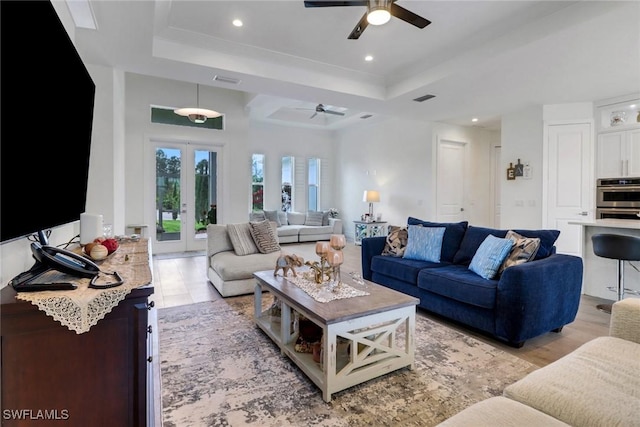 living room featuring a tray ceiling, french doors, visible vents, and recessed lighting