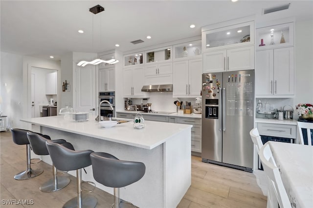 kitchen featuring a breakfast bar, stainless steel appliances, visible vents, light wood-style flooring, and white cabinets