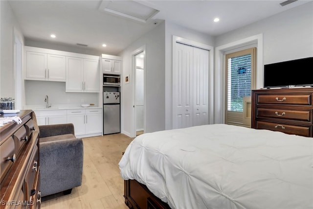 bedroom featuring recessed lighting, attic access, freestanding refrigerator, a sink, and light wood-type flooring