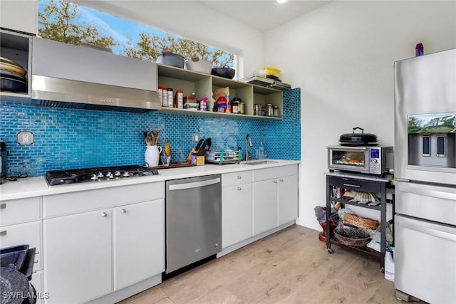 kitchen with stainless steel appliances, backsplash, a sink, and wall chimney range hood