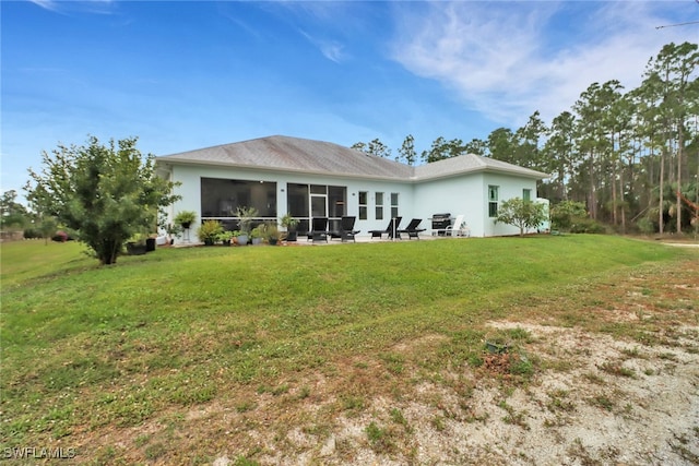 back of house with a sunroom, a lawn, and stucco siding