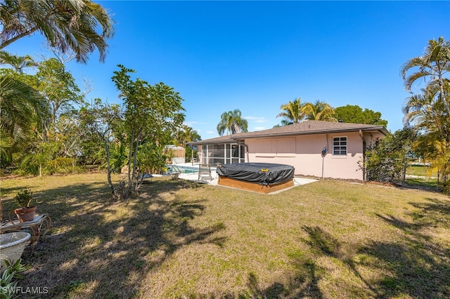 back of property featuring a lawn, an outdoor pool, a sunroom, and stucco siding