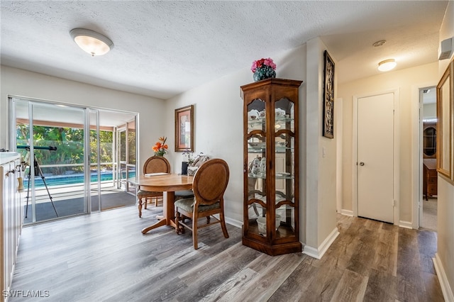 dining area featuring a textured ceiling, wood finished floors, and baseboards