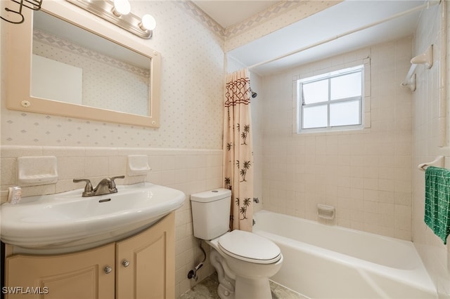 full bathroom with toilet, shower / tub combo, vanity, wainscoting, and wallpapered walls