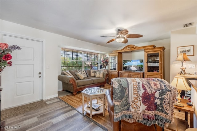 living area featuring light wood-type flooring, visible vents, ceiling fan, and baseboards