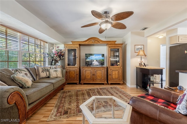 living area featuring light wood-style floors, visible vents, baseboards, and a ceiling fan