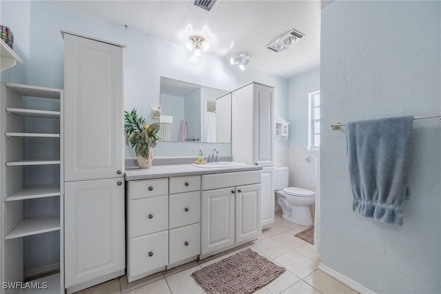 full bathroom with tile patterned flooring, toilet, visible vents, vanity, and tile walls