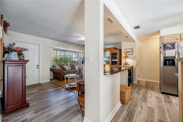 kitchen with stainless steel fridge, visible vents, and wood finished floors